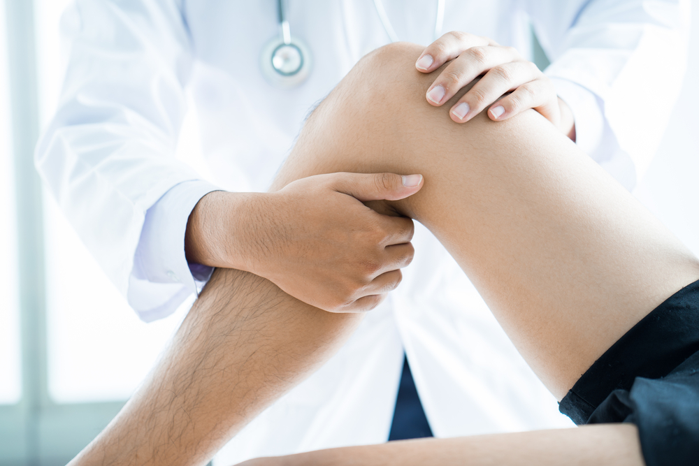 Doctor examining a patients leg during a sports/employment physical