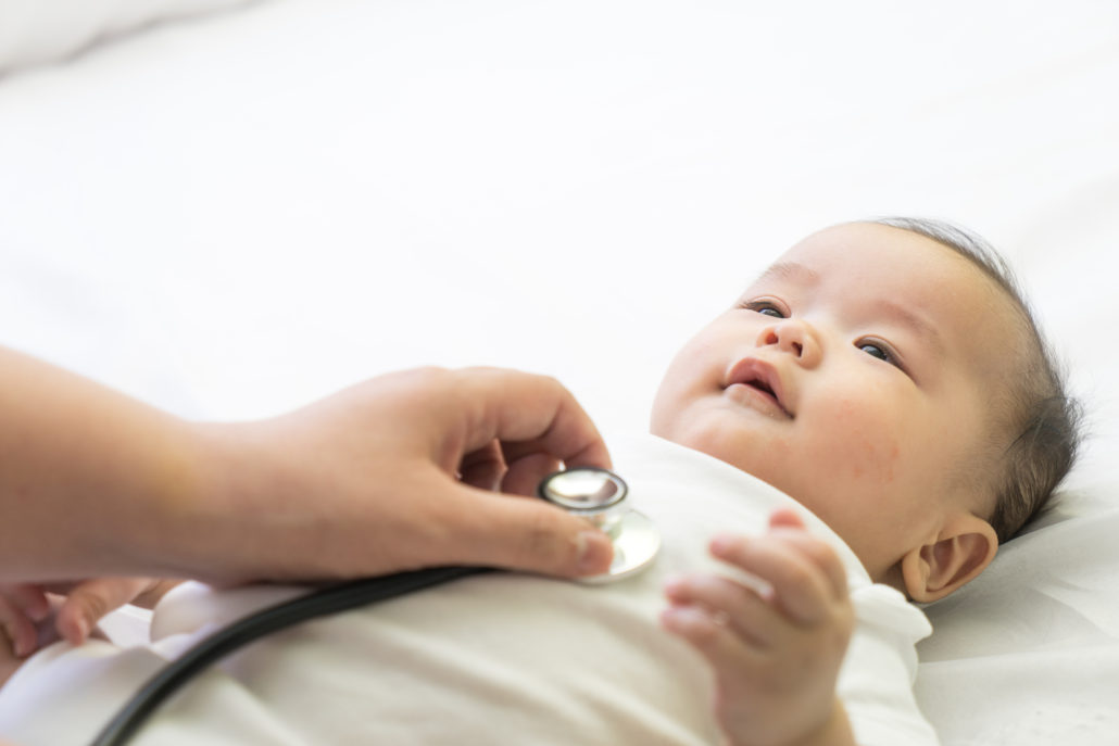 Doctor exams newborn baby with stethoscope in the hospital