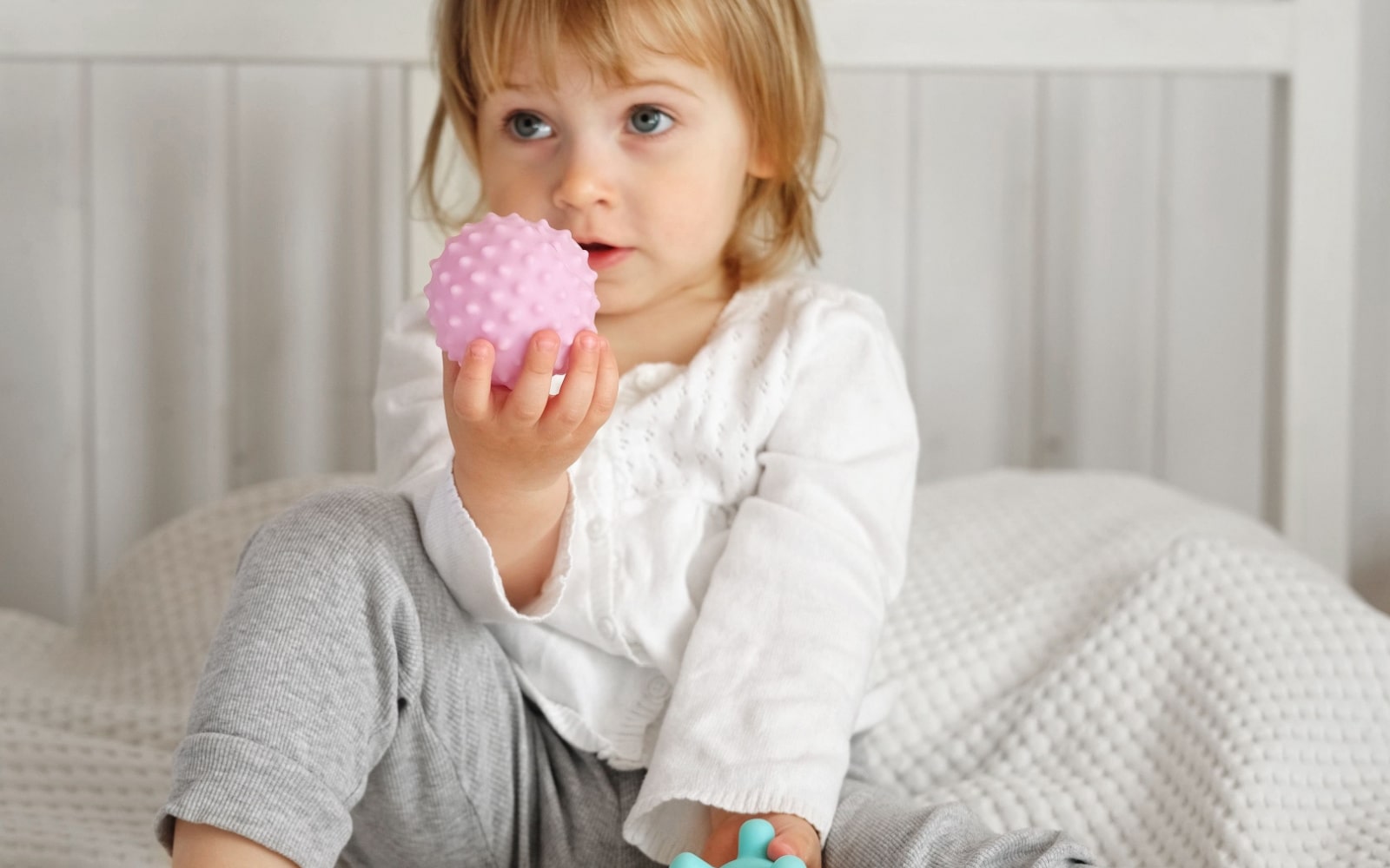 Child Looking at Camera Holding Toys